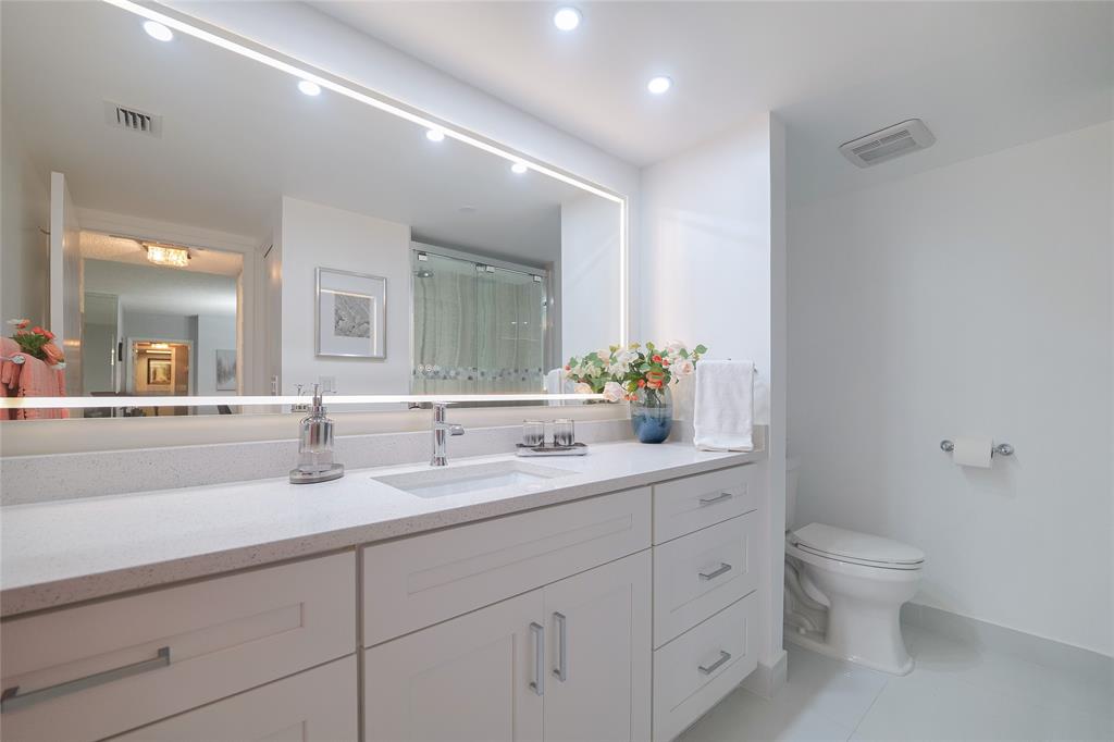 7300 Radice Court, Unit 404 Lauderhill, FL 33319 - Photo 34 of 85 a bathroom with a double vanity sink toilet and a mirror