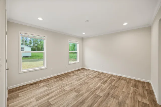 an empty room with wooden floor and windows