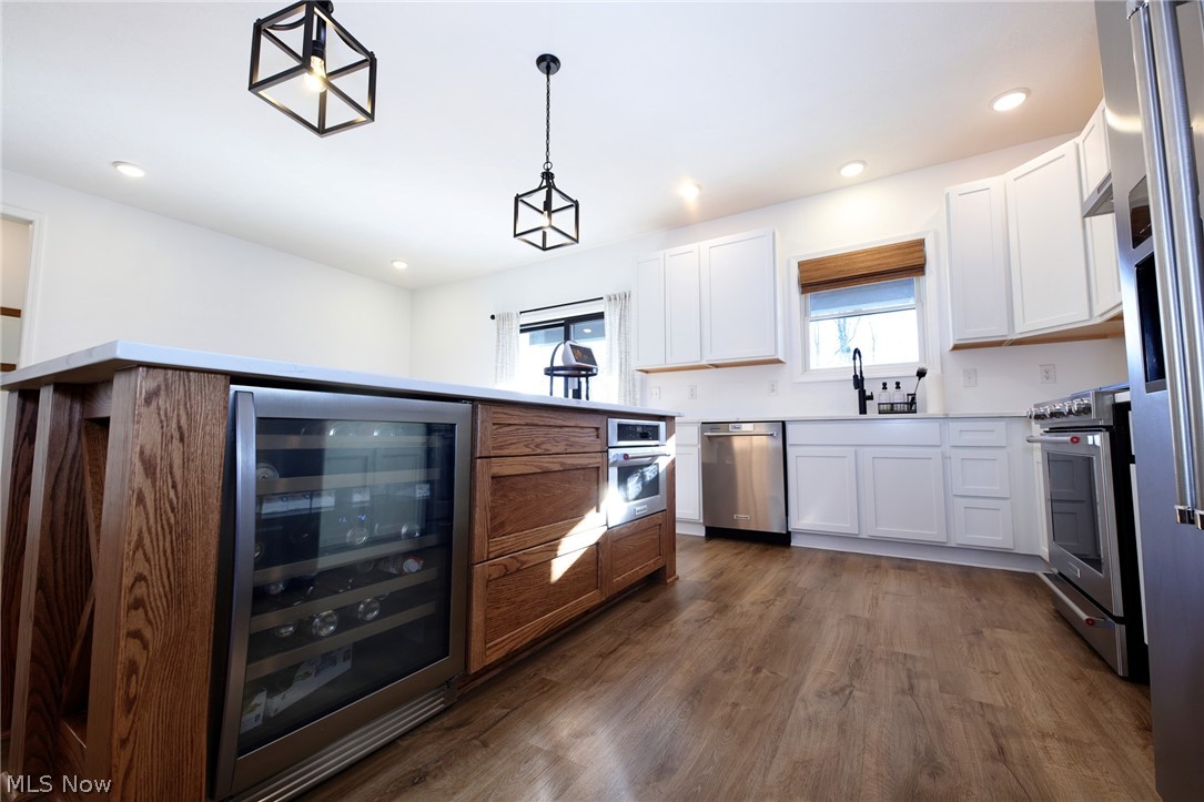 258 Friendly Acres Road Wellsburg, WV 26070 - Photo 7 of 47 Eat-In Kitchen featuring white cabinetry, wine cooler, stainless steel appliances, hanging light fixtures, and wood-style floors