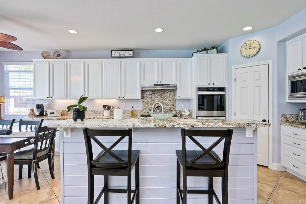 1738 Star Crest Place San Marcos, CA 92078 - Photo 17 of 51 a kitchen with stainless steel appliances granite countertop a table chairs sink and cabinets