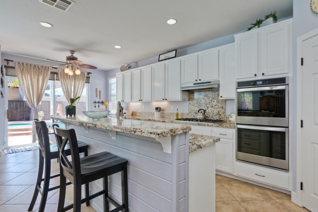 1738 Star Crest Place San Marcos, CA 92078 - Photo 18 of 51 a kitchen with kitchen island granite countertop white cabinets and stainless steel appliances