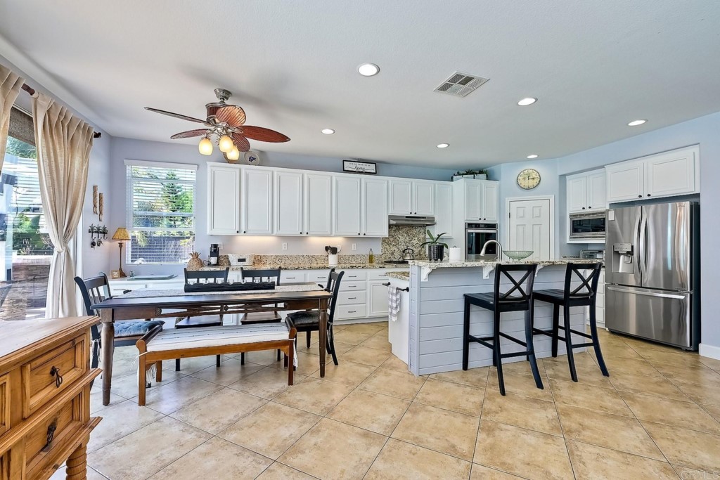 1738 Star Crest Place San Marcos, CA 92078 - Photo 20 of 51 a kitchen with stainless steel appliances kitchen island granite countertop a table chairs sink and cabinets