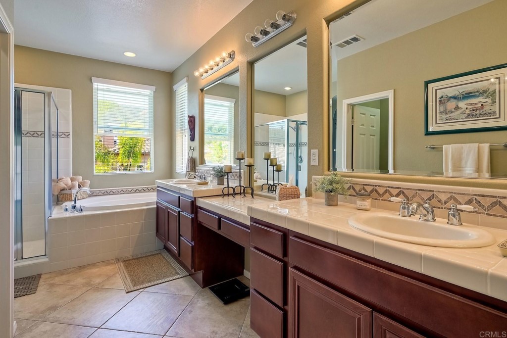 1738 Star Crest Place San Marcos, CA 92078 - Photo 30 of 51 a large bathroom with a double vanity sink a large mirror and a bathtub next to a window