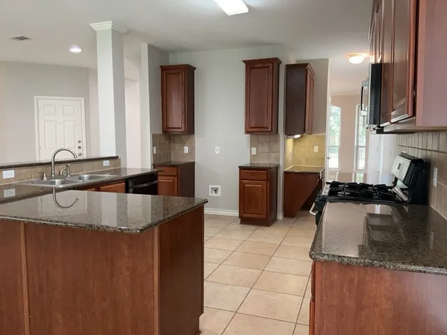 a kitchen with stainless steel appliances granite countertop a sink counter space cabinets and a large window