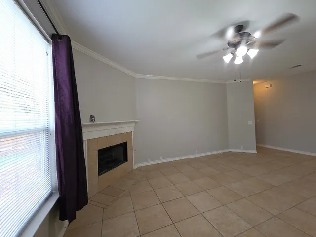 a view of an empty room with chandelier fan and fire place
