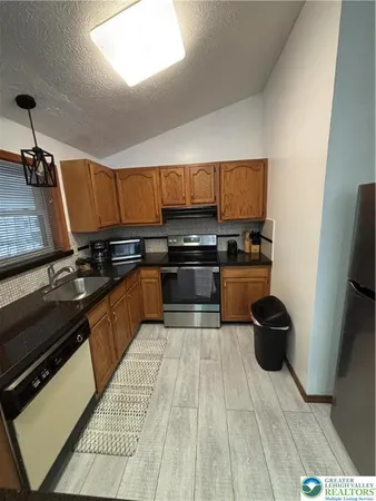 a kitchen with stainless steel appliances a stove a sink a refrigerator and a microwave
