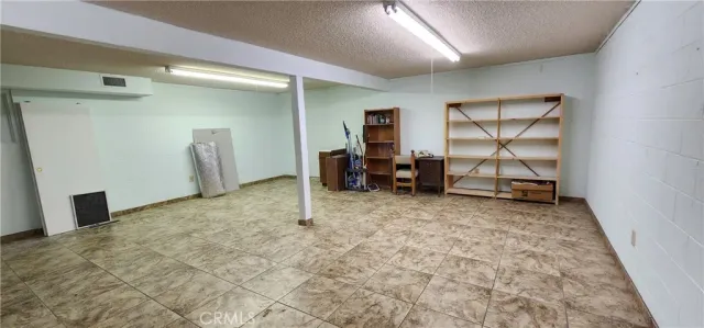 a view of an empty room with kitchen and a window