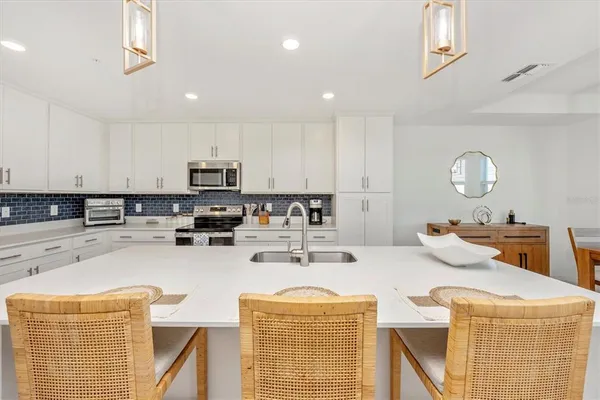 a living room with stainless steel appliances furniture a rug kitchen view and a large window