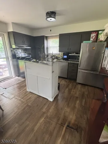 a living room with stainless steel appliances furniture and a kitchen view