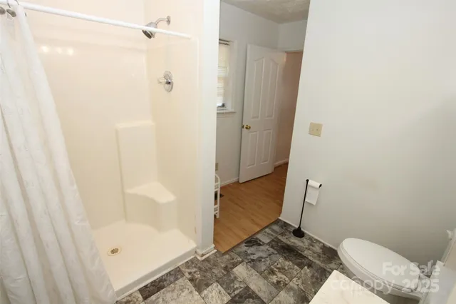 a bathroom with a granite countertop shower and a toilet