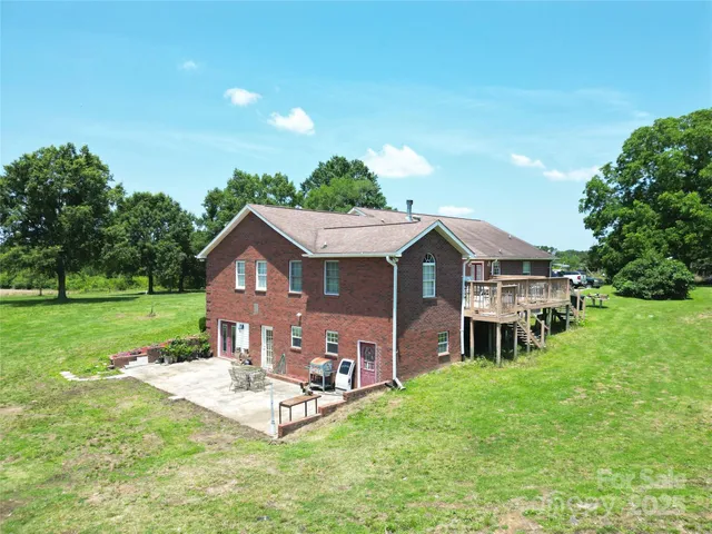 a view of a house with a big yard plants and large trees