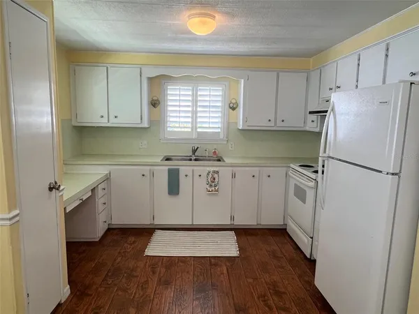 a kitchen with a refrigerator a sink and dishwasher with wooden floor