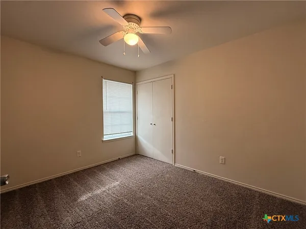 an empty room with windows and fan