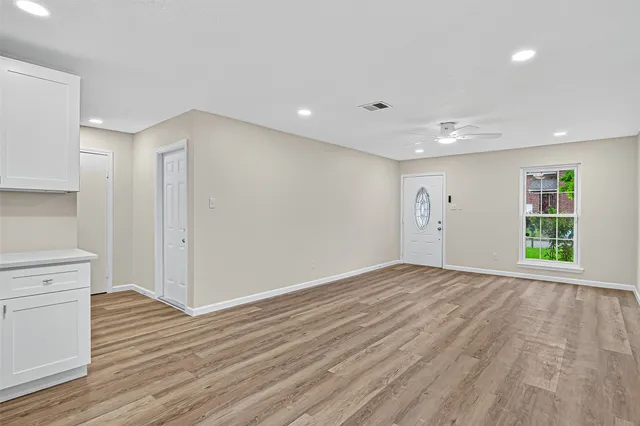 a view of an empty room with wooden floor and a window