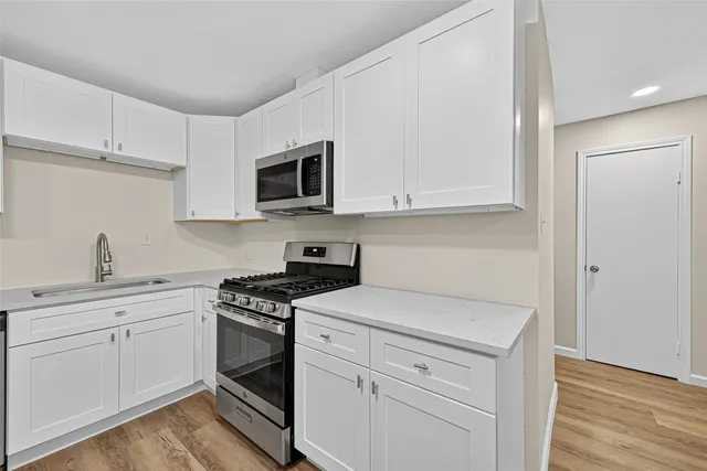 a kitchen with white cabinets stainless steel appliances and sink
