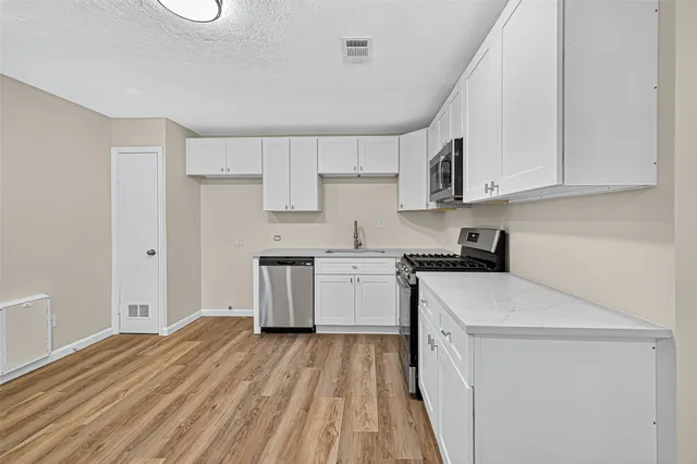 a kitchen with a sink a stove top oven and white cabinets