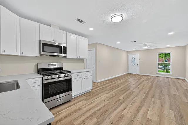 a kitchen with stainless steel appliances granite countertop a stove a sink and a microwave