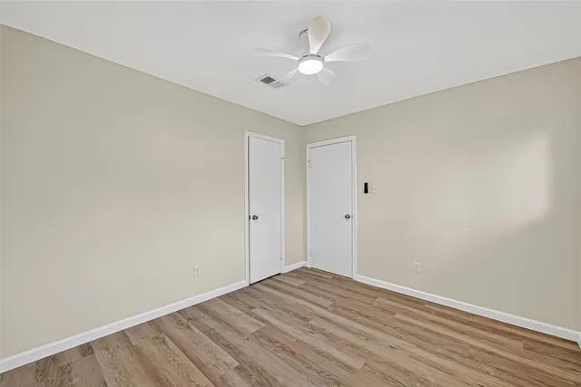 a view of a room with wooden floor and a ceiling fan
