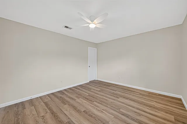 a view of a room with wooden floor and a ceiling fan