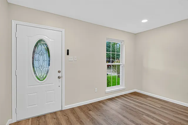 an empty room with wooden floor a mirror and a window
