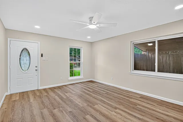 a view of an empty room with wooden floor and window