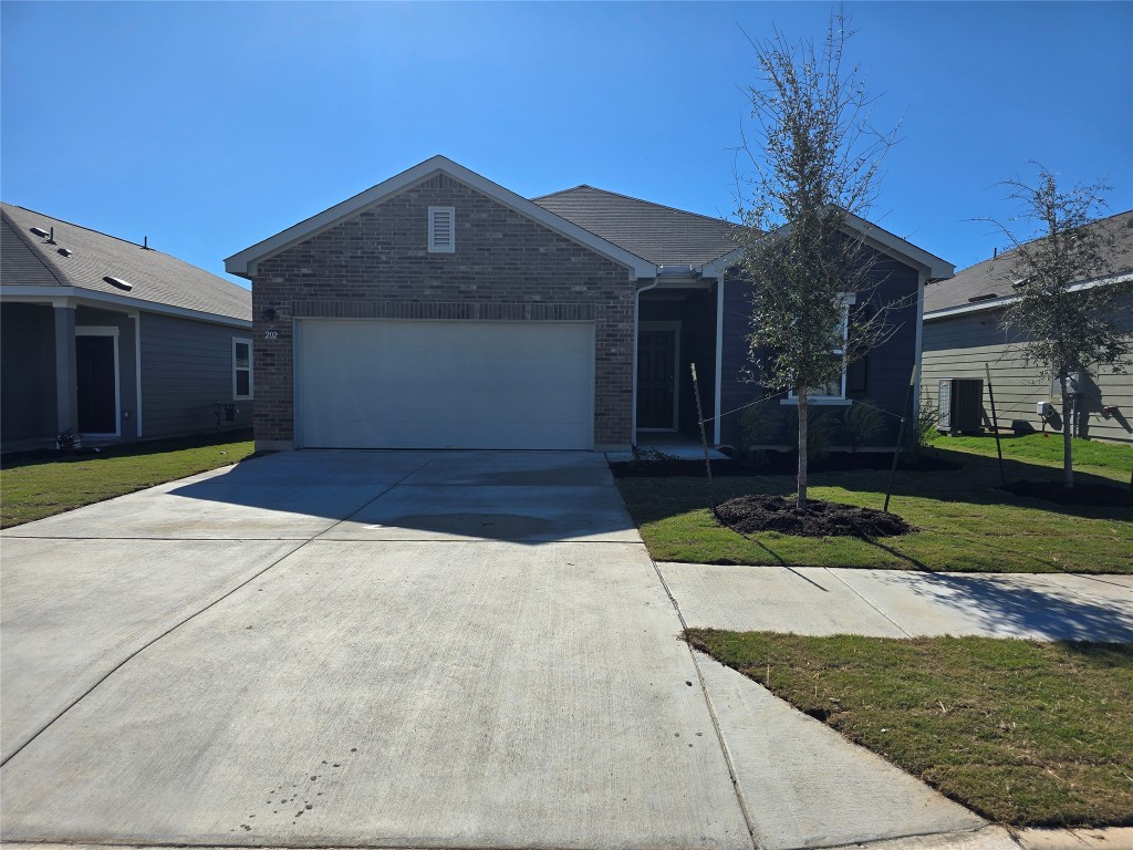 Single story home featuring brick siding, concrete driveway, a front yard, and an attached garage