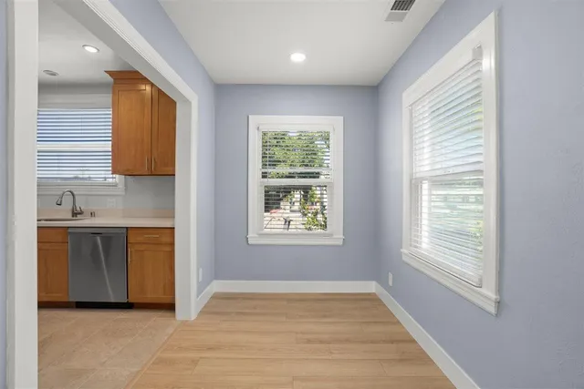 a view of an empty room with a window and a kitchen