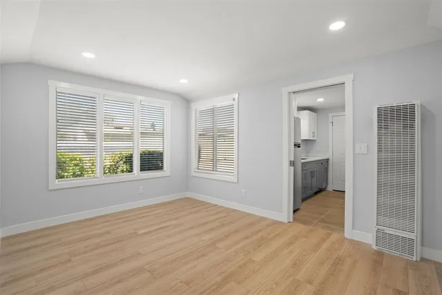 a view of an empty room with wooden floor and a window