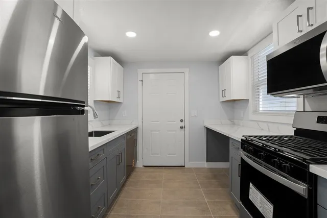 a kitchen with stainless steel appliances a sink a stove a microwave a refrigerator a cabinets and a wooden floor