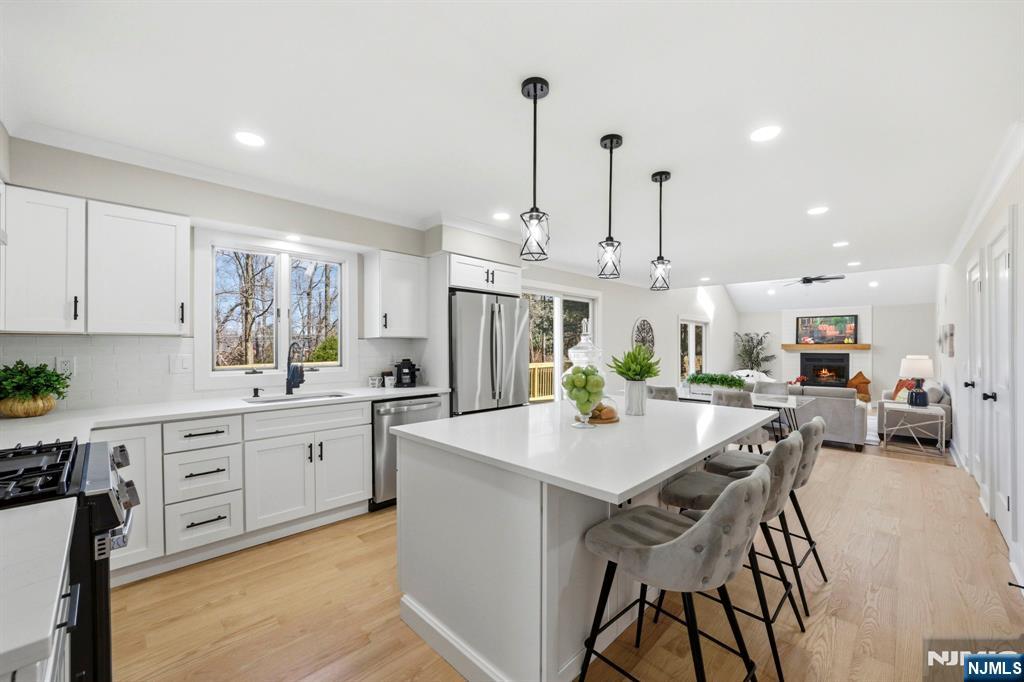 34 Knob Hill Road Morganville, NJ 07751 - Photo 14 of 50 a kitchen with stainless steel appliances kitchen island granite countertop a stove a sink a dining table and chairs with wooden floor