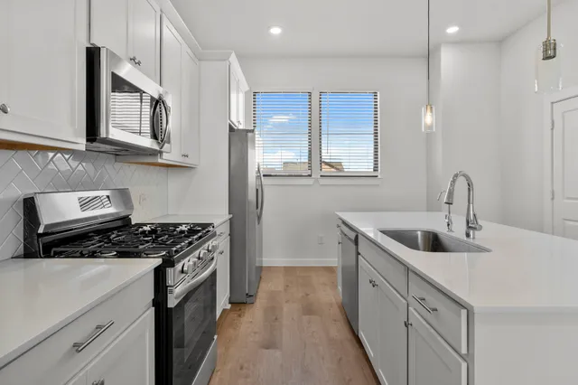 a kitchen with stainless steel appliances white cabinets and a stove top oven