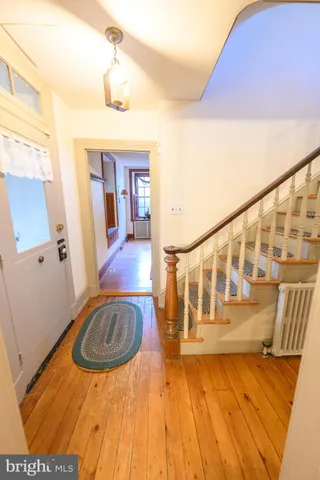 a view of a bedroom with wooden floor a ceiling fan and windows