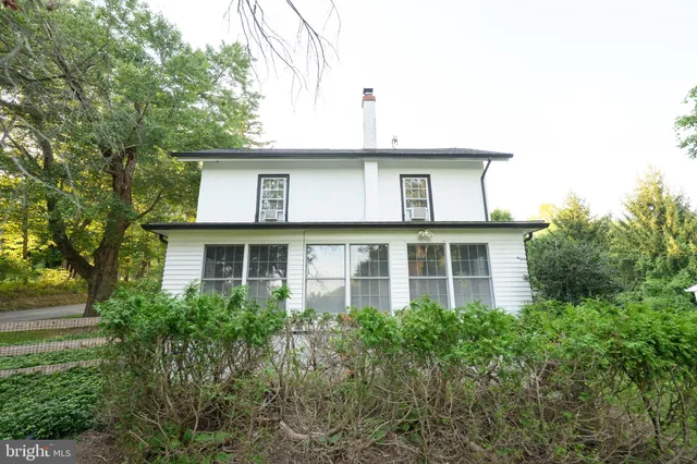 a white house with a small yard and large trees
