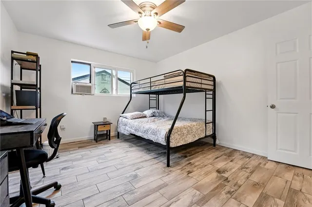 a bedroom with a bed a desk and chair with wooden floor