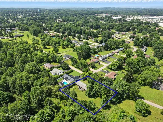 an aerial view of residential houses with outdoor space and trees