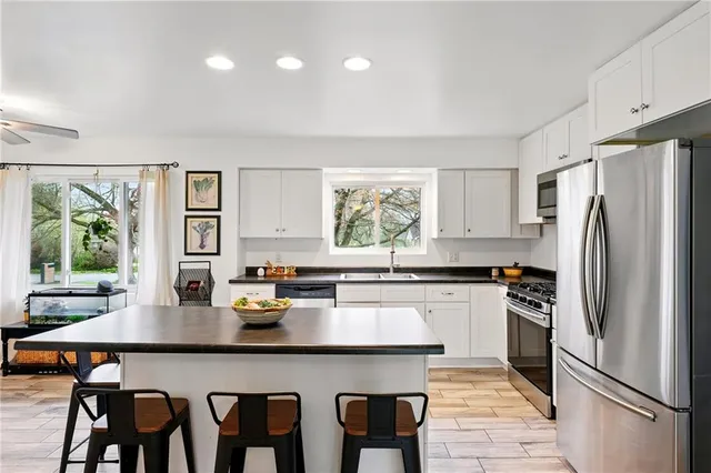 a kitchen with granite countertop a refrigerator a stove a dining table and chairs