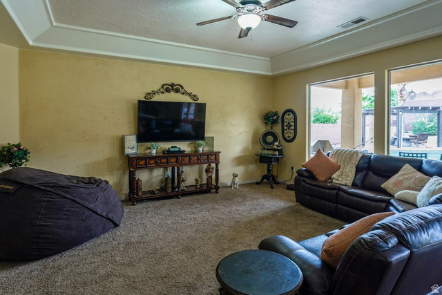 3683 South 2640 West St. George, UT 84790 - Photo 18 of 41 Living room featuring tray ceilings with a ceiling fan, textured walls, and carpet flooring