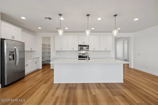 a large white kitchen with kitchen island a sink a center island stainless steel appliances and a fireplace