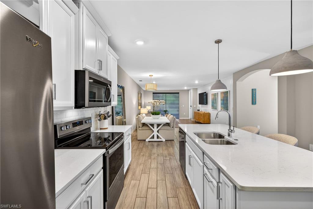 14567 Edgewater Circle Naples, FL 34114 - Photo 12 of 43 a kitchen with stainless steel appliances kitchen island hardwood floor sink stove and microwave