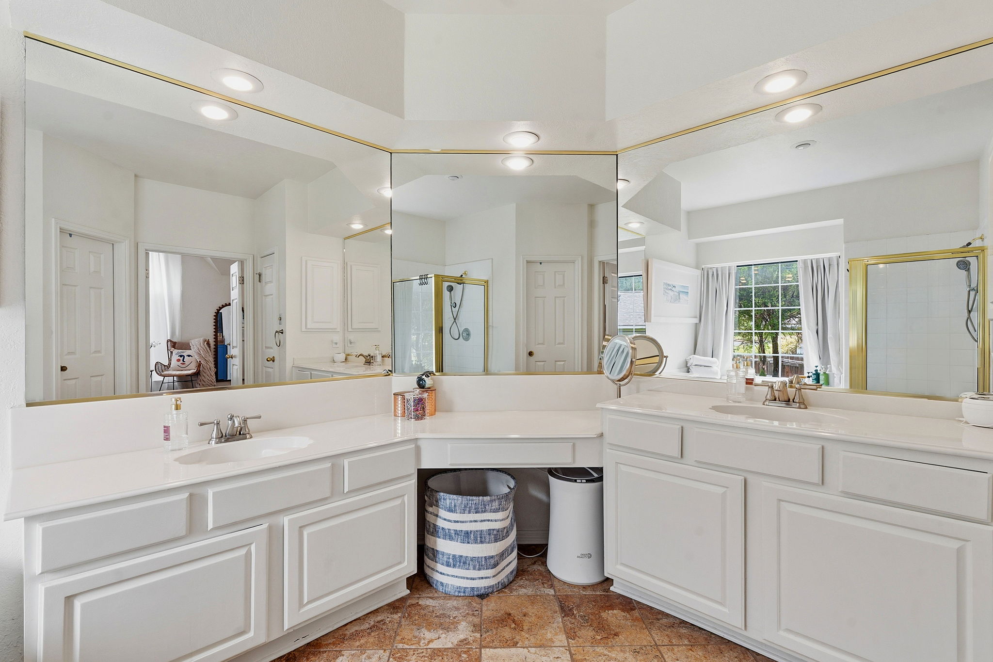 8317 Pommel Drive Austin, TX 78759 - Photo 14 of 26 A well-lit primary bathroom features dual vanities, ample counter space, and a large mirror extending to the vaulted ceiling.