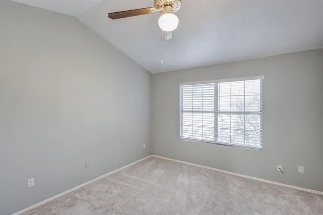 an empty room with chandelier fan and windows