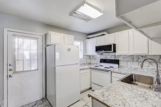 a kitchen with a refrigerator a microwave a sink and cabinets