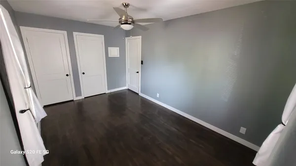 en empty room with wooden floor and fan