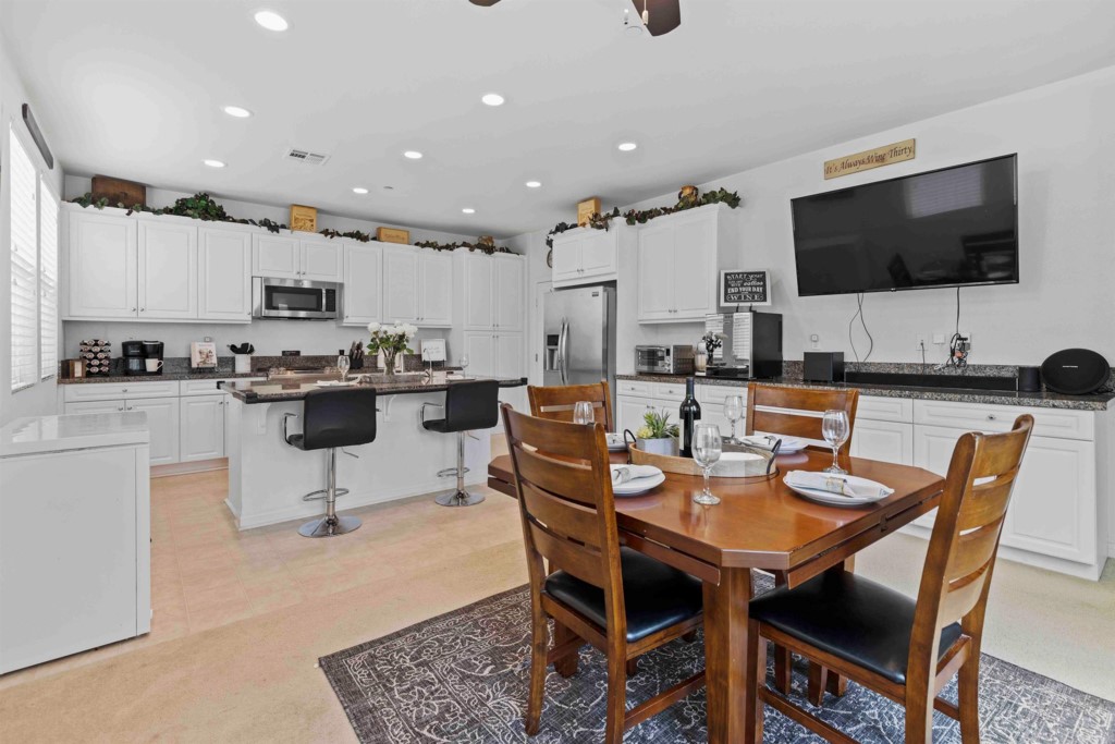 a dining room with stainless steel appliances kitchen island granite countertop a table chairs and a microwave