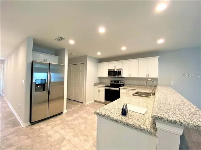 a kitchen with granite countertop a sink a stove and refrigerator