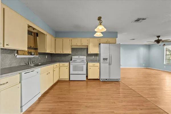 a view of an empty room with wooden floor and ceiling fan