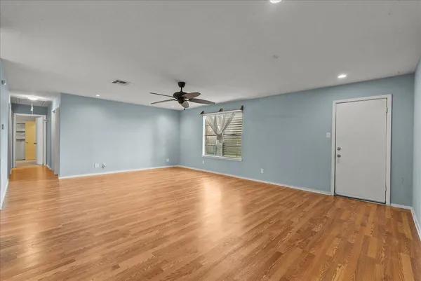 a view of an empty room and chandelier fan