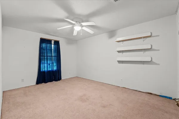 an empty room with a fan & a window