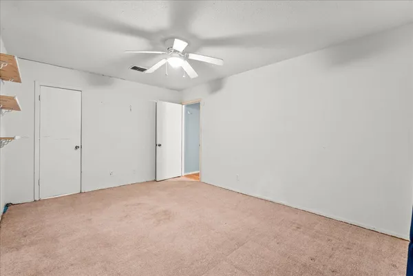 an empty room with a fan & a window