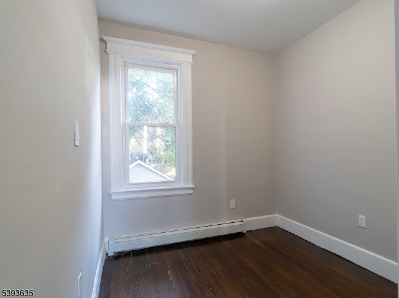 134 Maple Avenue Irvington, NJ 07111 - Photo 19 of 29 an empty room with wooden floor and windows